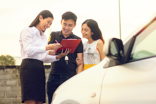 Couple purchasing and signing sales contract for car at dealership