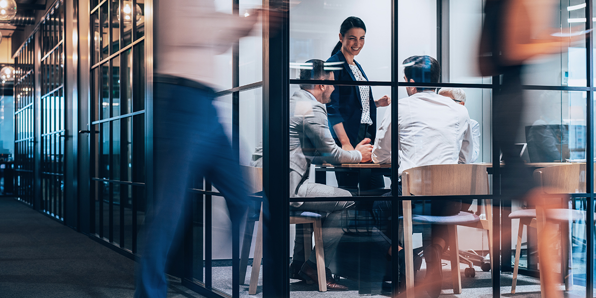 Two office workers walking past a meeting room