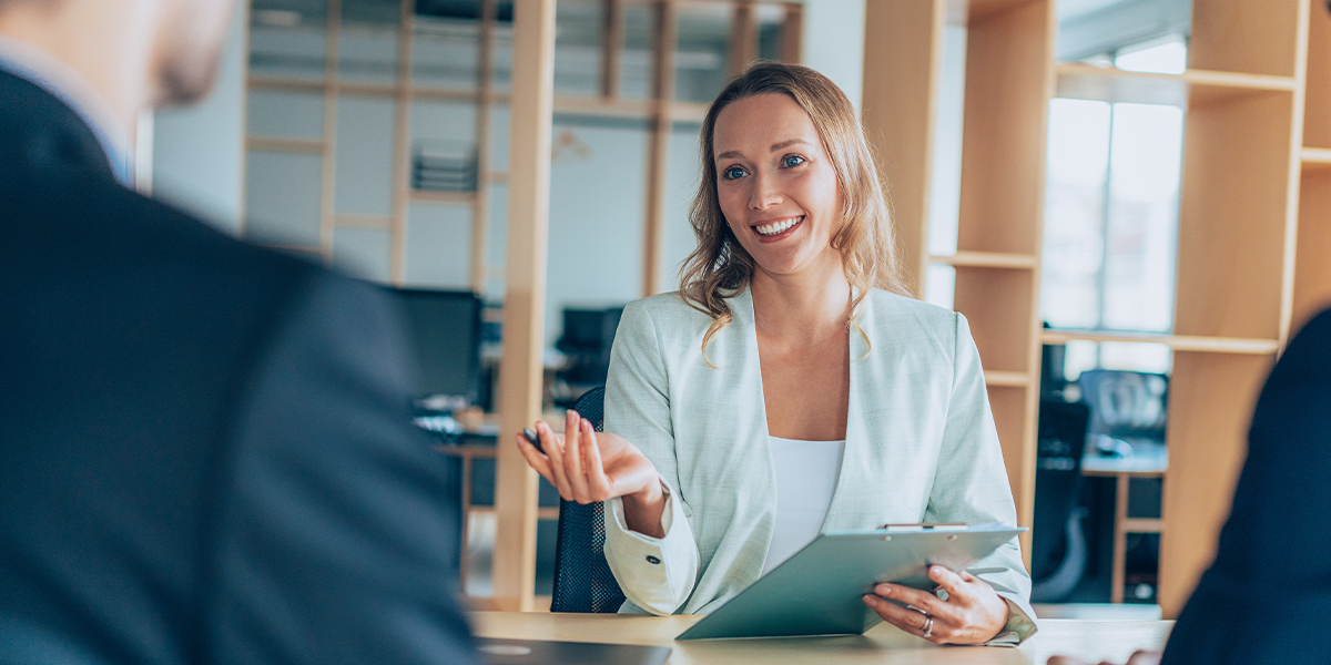 female mortgage broker holding clipboard talking to clients